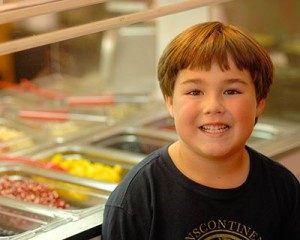 Boy smiling in front of food counter.