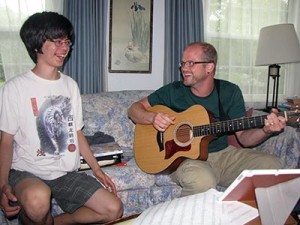 Mackenzie smiling while a Noble therapist plays guitar.