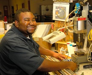 Noble participant smiling while working with factory machinery.