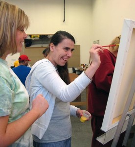 Noble participant smiling while painting.