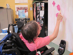 Noble participant painting on canvas from her wheelchair.