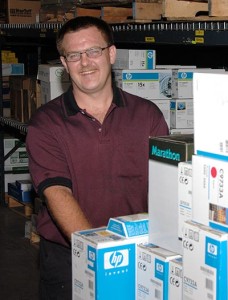 Tony smiling while pulling a handtruck in warehouse..