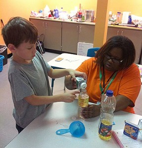 Camper and counselor working on a science experiment together.