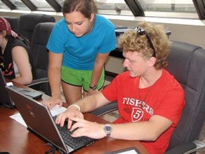 Noble employee assisting young man typing on a laptop.