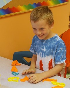 Smiling boy using PlayDoh at handwriting camp