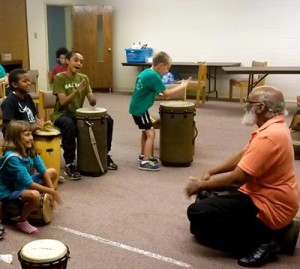 Kids smiling and playing music during Music and Dance Camp.