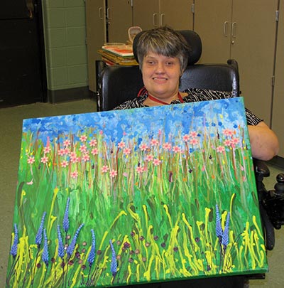 Lisa Thacker holding her a colorful art piece that she painted.